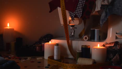 vintage background shot of a sewing machine, threads, buttons and candles, with dust flying around