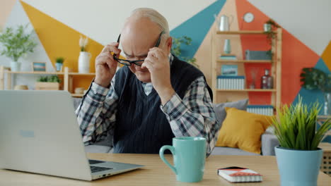 hombre mayor usando computadora portátil en casa