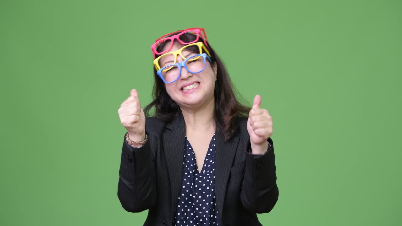 Mature beautiful Asian businesswoman wearing many eyeglasses as funny concept