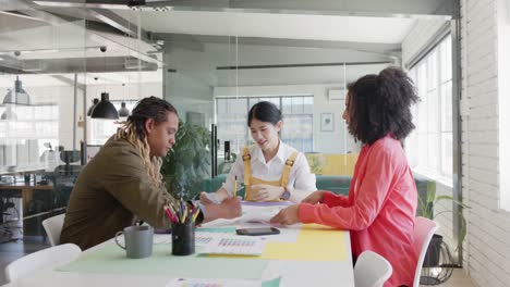 busy diverse business creatives at table discussing work in casual office meeting, in slow motion