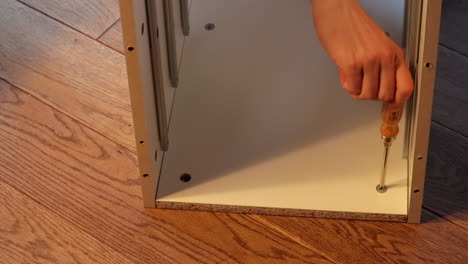 close up of boy hand assembling shelf parts on the floor