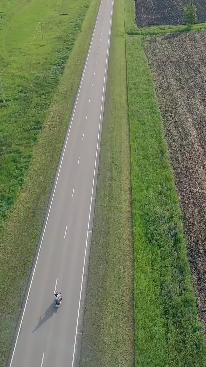 wonderful upper view people on modern motorbike drives along gray road near brown field lit by sunlight