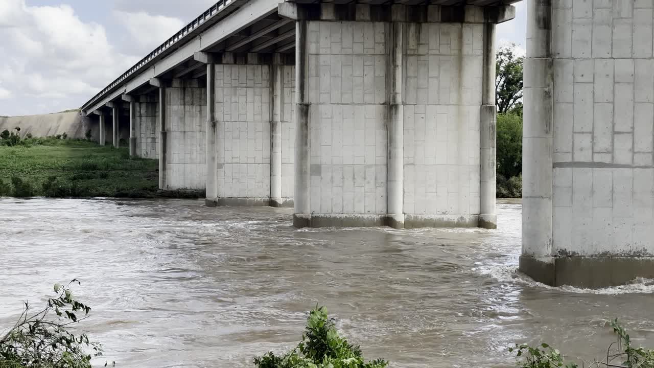 Flooded river flowing quickly below a bridge