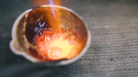 drop of molten gold heats in fireproof cup extreme closeup