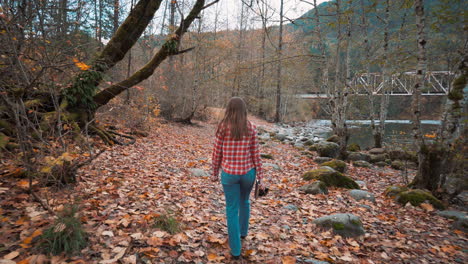 photographer woman walks along riverside among fall colors and takes polaroid