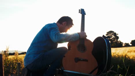 musician takes guitar from case golden hour