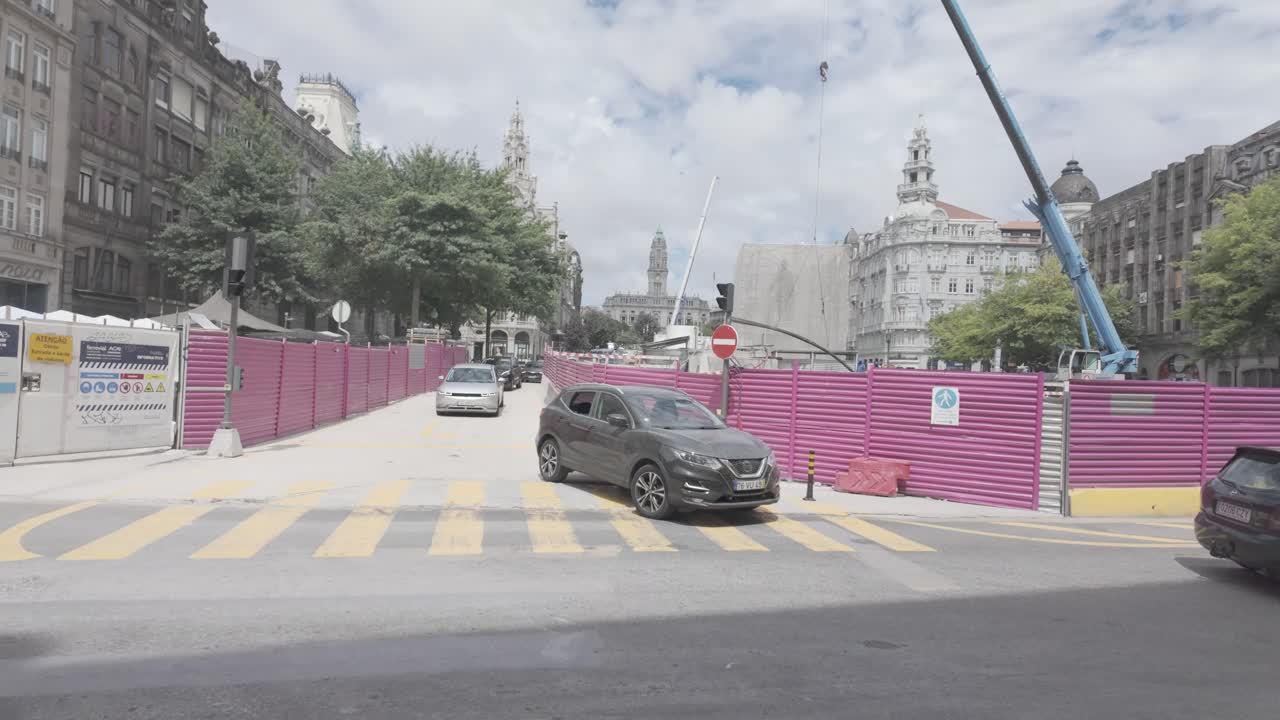 Construction work in Praça da Liberdade, Porto, with traffic and a crane on a cloudy day