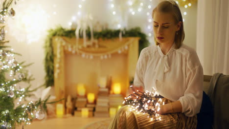 woman arranges christmas decorations and untangles lights at home