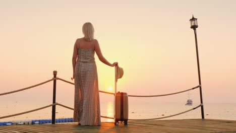 una mujer solitaria llegó a un balneario de pie en un muelle mirando a lo lejos en las olas del mar