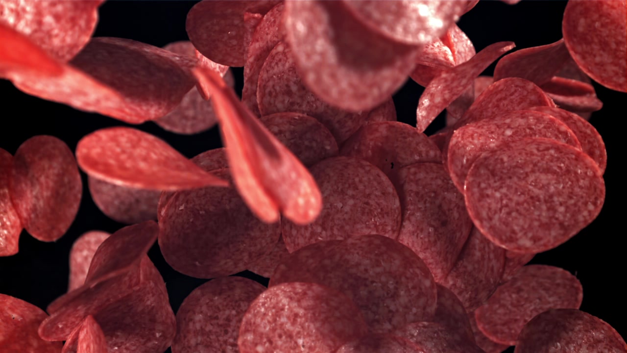Molte fette di pepperoni che cadono su uno sfondo nero