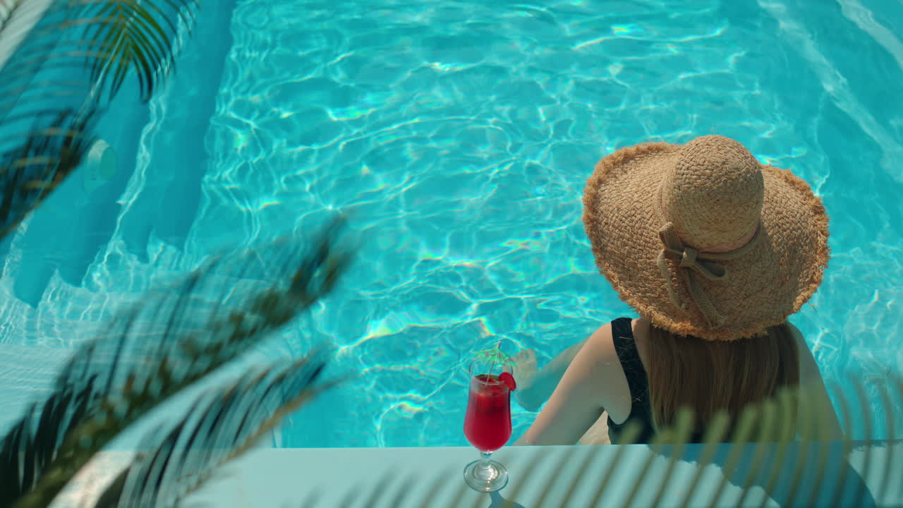 Frau entspannt sich mit einem Cocktail im Schwimmbad