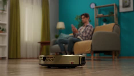 robot vacuum cleaner in a living room with a man using phone