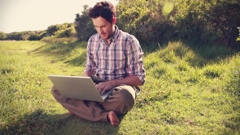 joven usando una computadora portátil en el campo