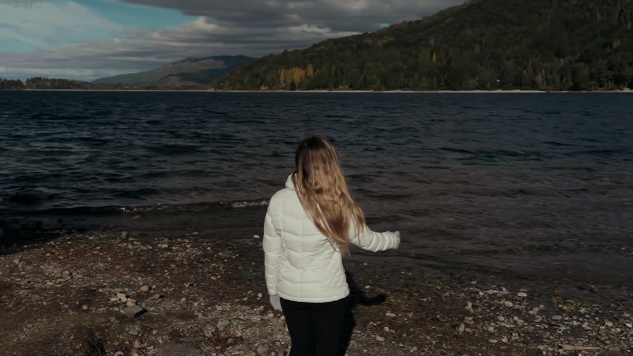 Woman playing throws a stone to a lake and laugh