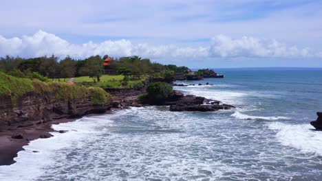 waves coming to the rocky shoreline near the tanah lot temple in summer in bali, indonesia