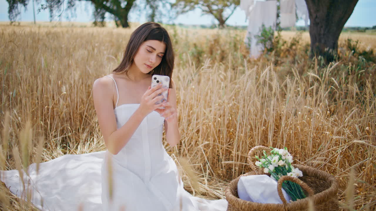 여름 에서 스마트폰을 사용하는 피크닉 모델. 편안한 담요에 앉아있는 편안한 소녀