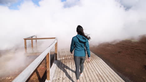 young woman confidently strides towards huge clouds of