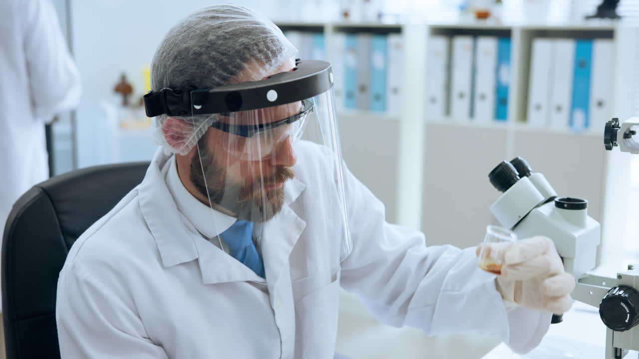 Male Scientist Examining Sample with Microscope in Laboratory