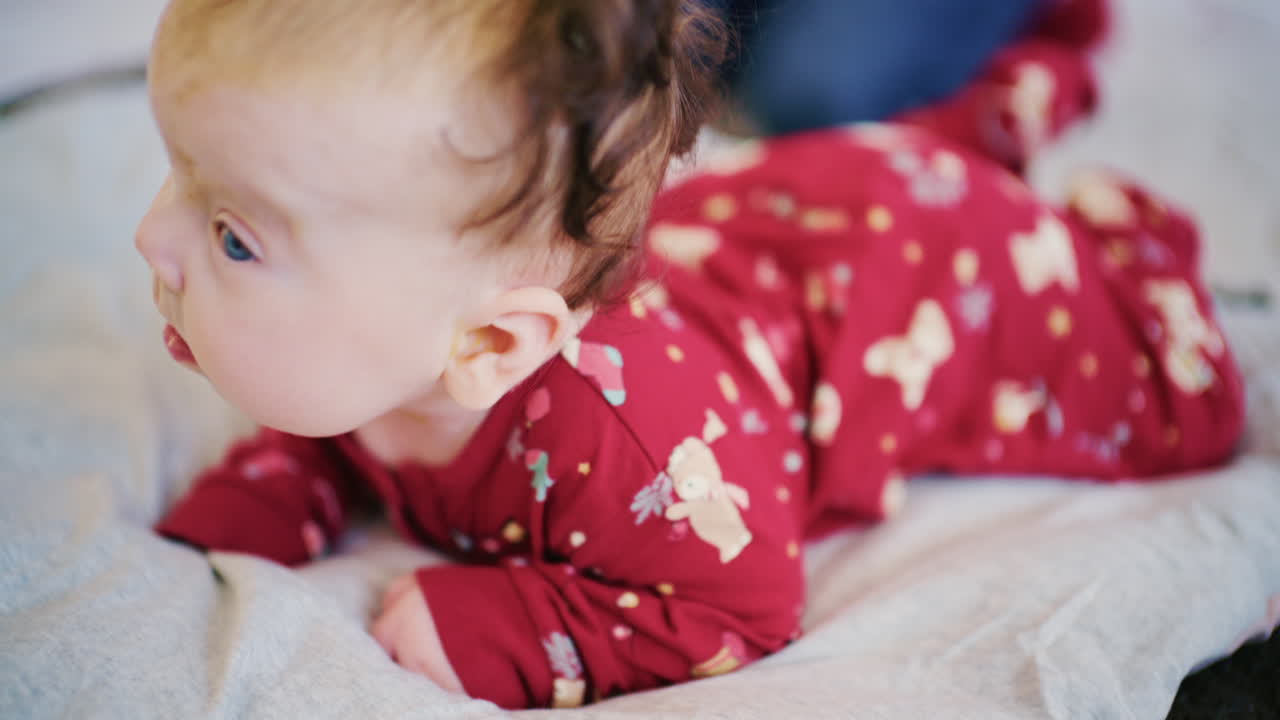 Bambino che pratica il tempo a pancia in giù su un letto morbido mentre solleva la testa e guarda in avanti.
