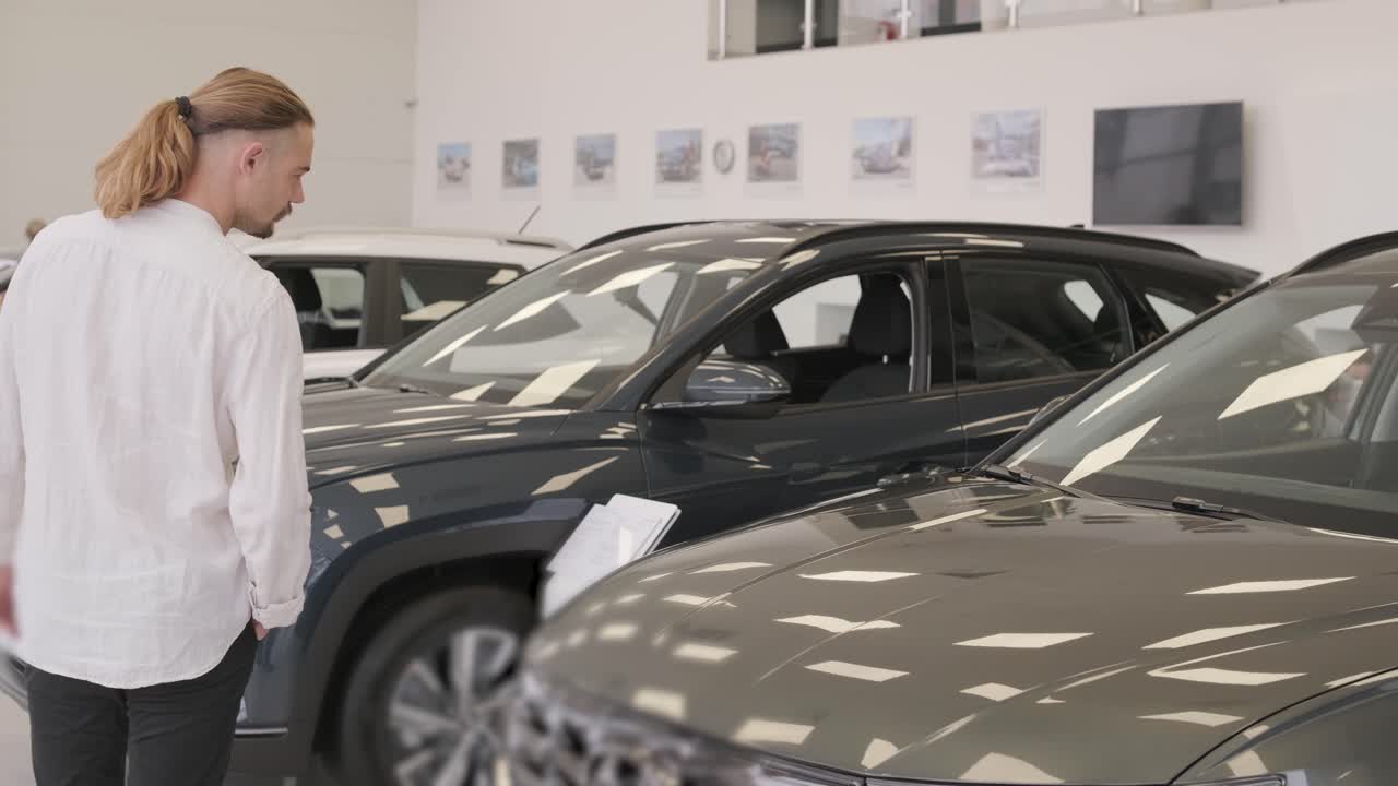 feliz barba de pelo largo cliente masculino en la sala de exhibición de vehículos, persona masculina que compra transporte, negocio de concesionarios de automóviles. hombre mirando el coche nuevo. consumidor en concesionario de automóviles, hombre de negocios eligiendo un coche.