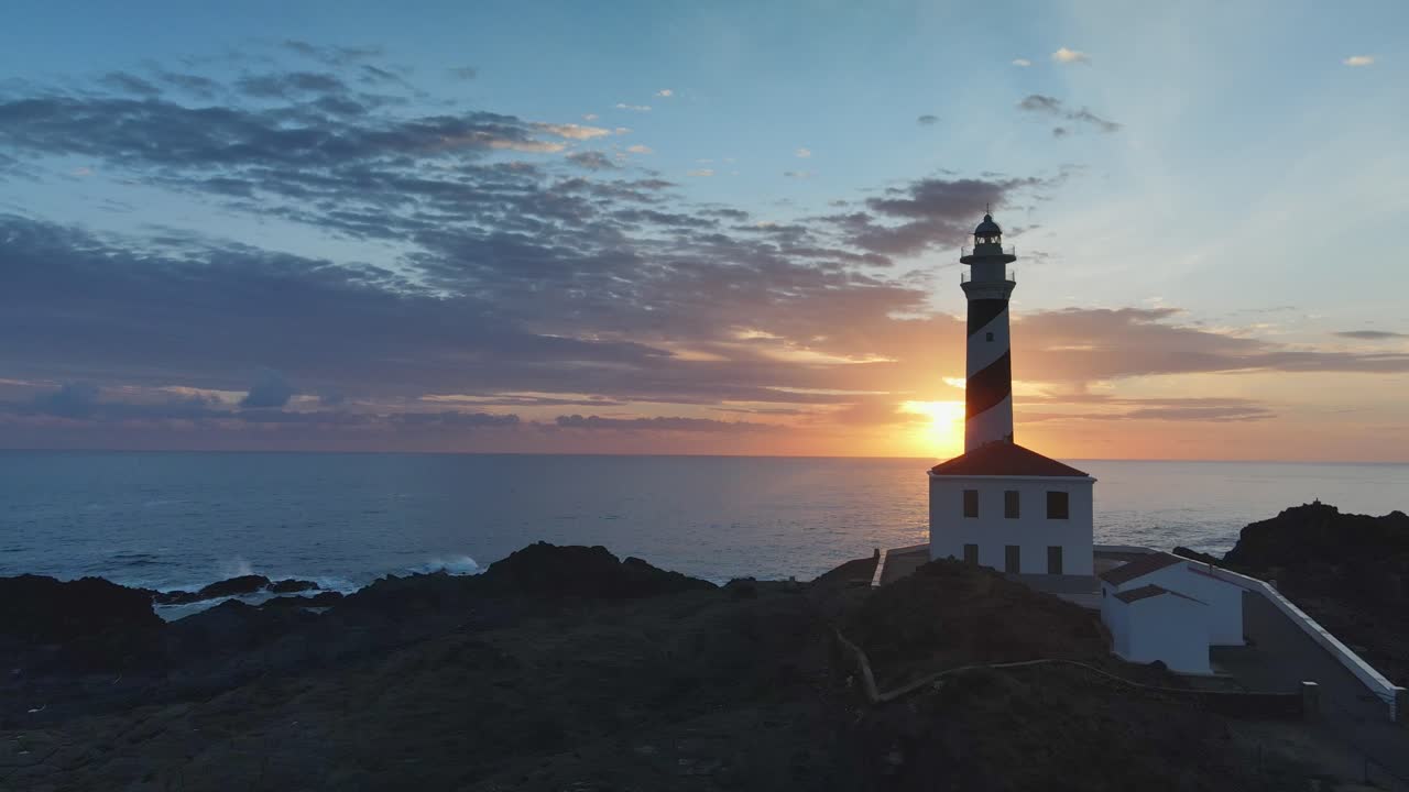 Lenta ascesa del drone con il sole che appare da dietro il faro di Favaritx a Minorca, Spagna