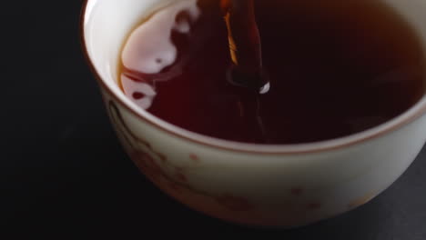 pouring tea into a small cup