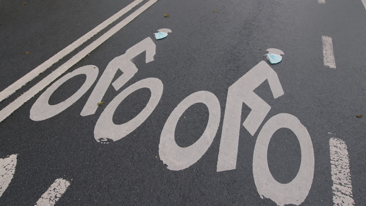 Camera Tilt Down From Person Riding Bike To Road Surface — Painted Bike Symbols Wearing Surgical Masks, Central Park, New York City