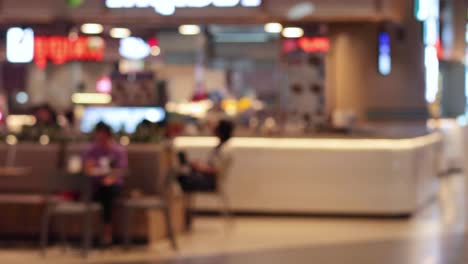 individual traverses a bustling, illuminated food court