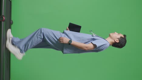 full body of side view asian male doctor with stethoscope holding a tablet while walking on green screen background in the hospital