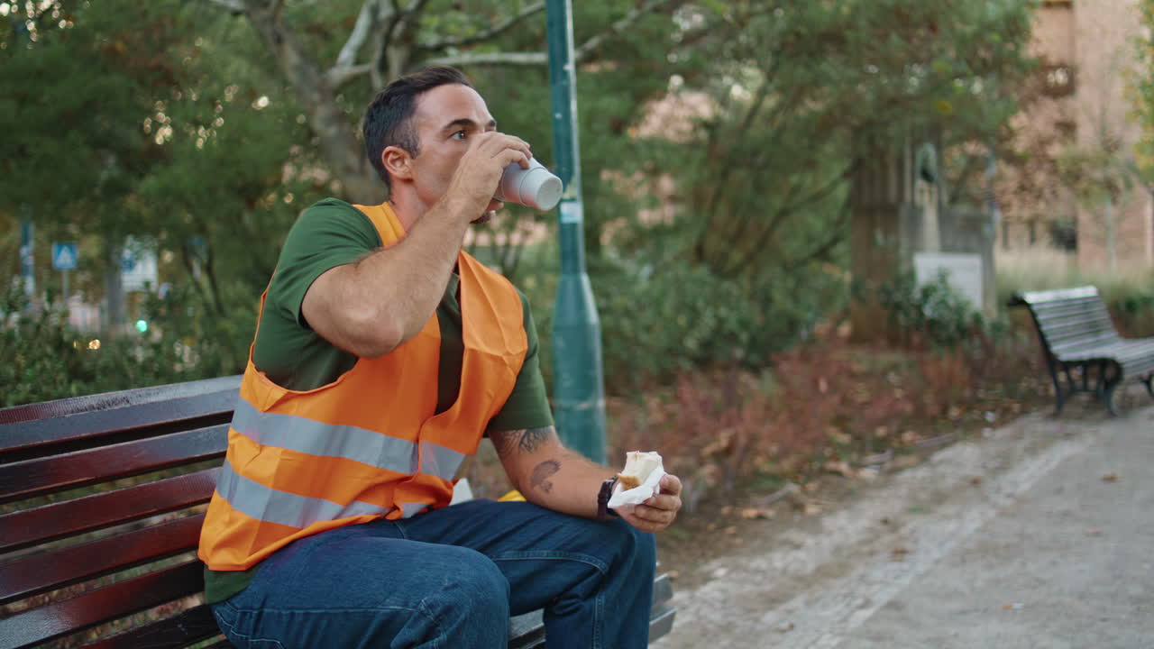 Uniform foreman drinking tea enjoying break at wooden bench alone. Man resting