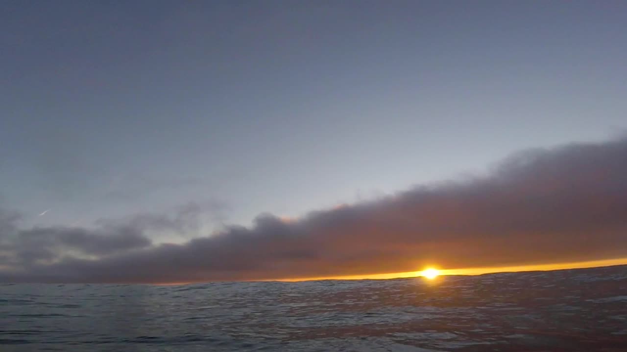 야외 활동 캠은 일몰 시간에 슬로우 모션으로 떠 있는 보디보드를 따라갑니다.