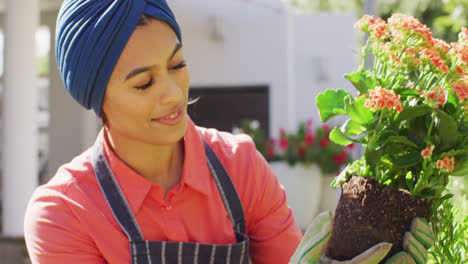 video of happy biracial woman in hijab planting flowers in garden