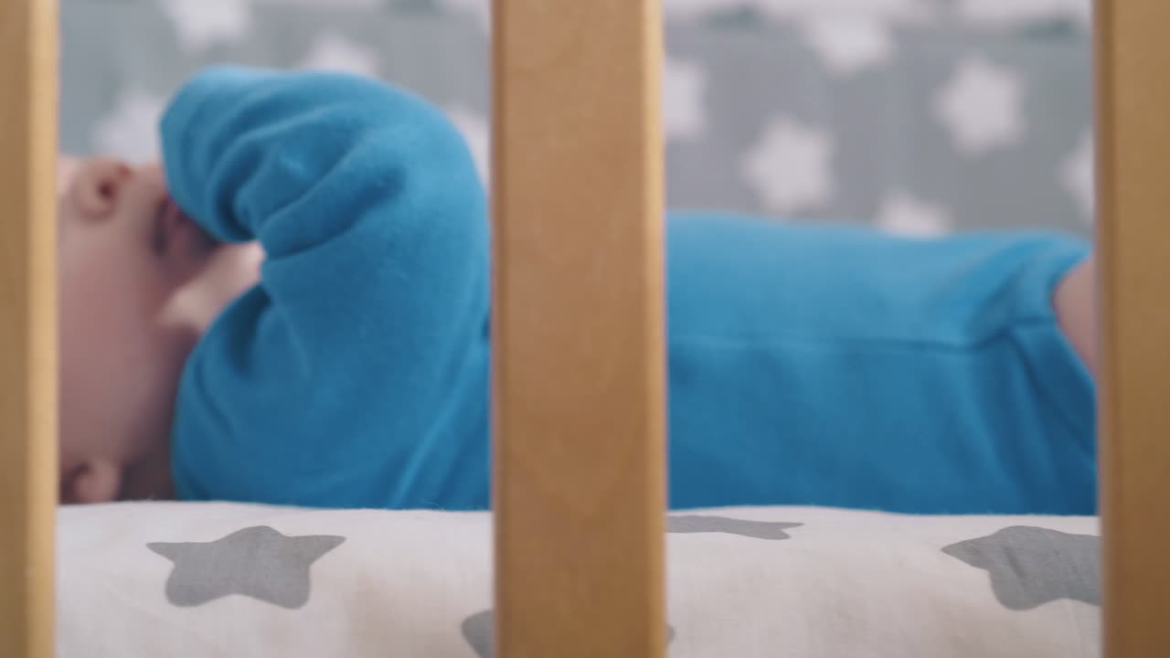 movimento lungo piccolo bambino in abiti blu giace in una culla di legno