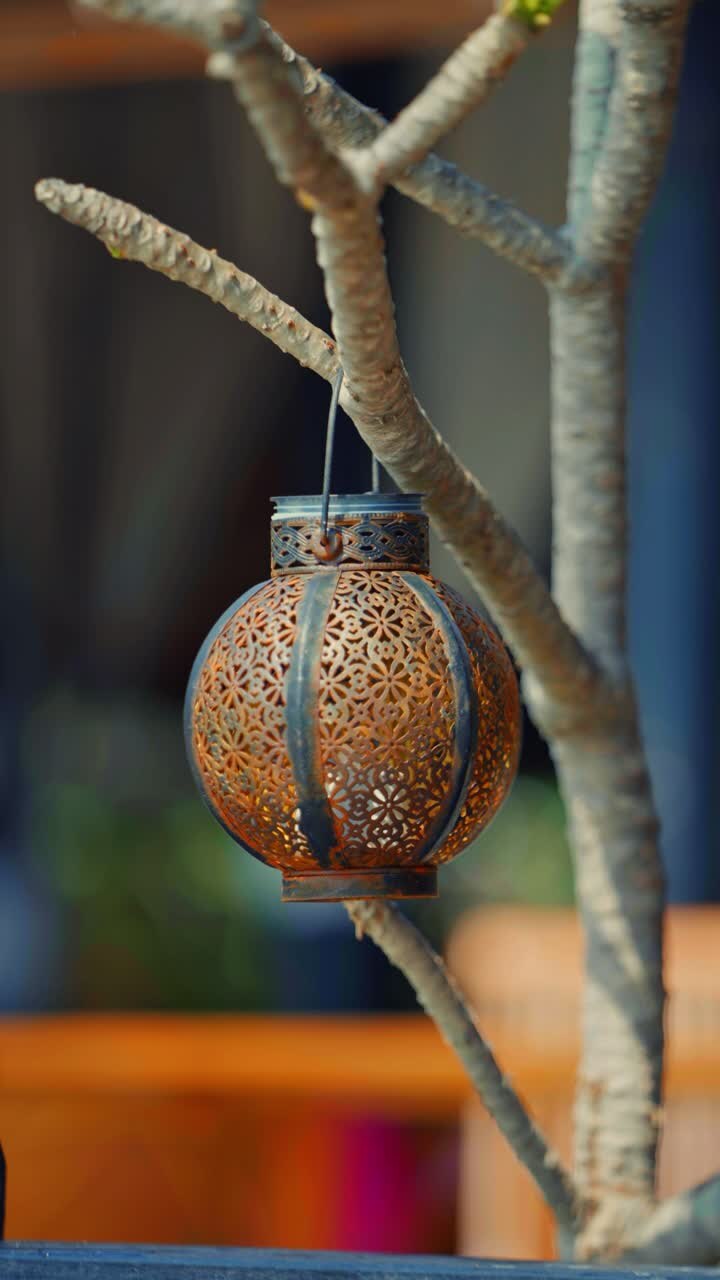 Traditional rusty metal lantern hanging from a tree branch, creating a warm and inviting atmosphere in Langkawi, Malaysia