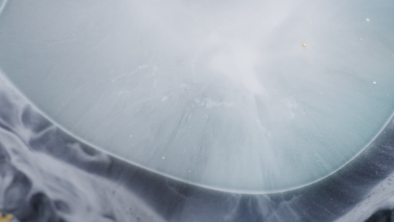 Drops of grey ink creating abstract shapes. Macro view