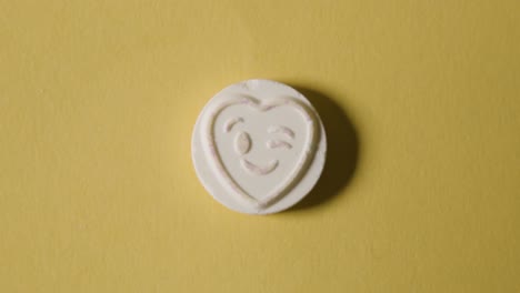 heart candy with winking emoji on yellow background