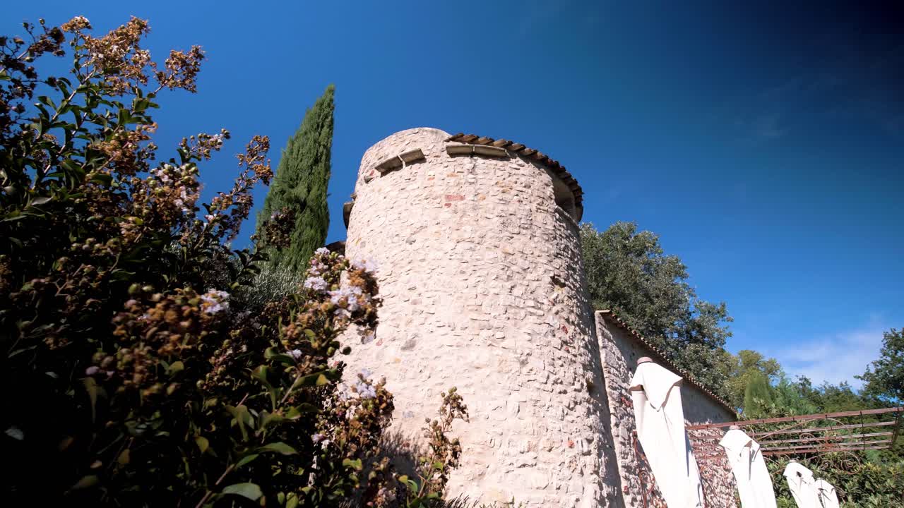 Slow establishing shot of a stone tower on a villa in Goult, France