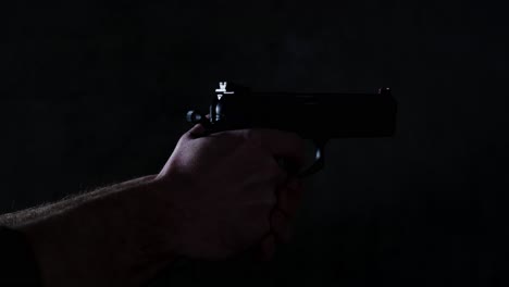 handgun being fired two times in a dark room