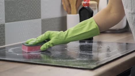 closeup of hand woman cleaning modern cooking glass ceramic electric surface with sponge and detergent