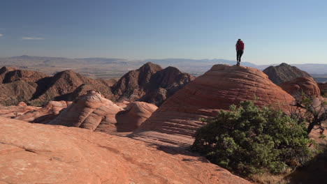 female hiker climbing on swirled rock formation in utah usa desert, yant flat candy cliffs hiking trail