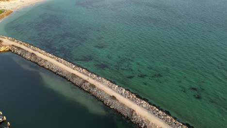 Aerial-tilt-down-shot-of-walking-tourist-in-jetty-surrounded-by-Pacific-Ocean-in-Fremantle,-Western-Australia