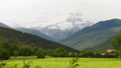 snow capped pyrenees mountains above green fertile valley, panning shot