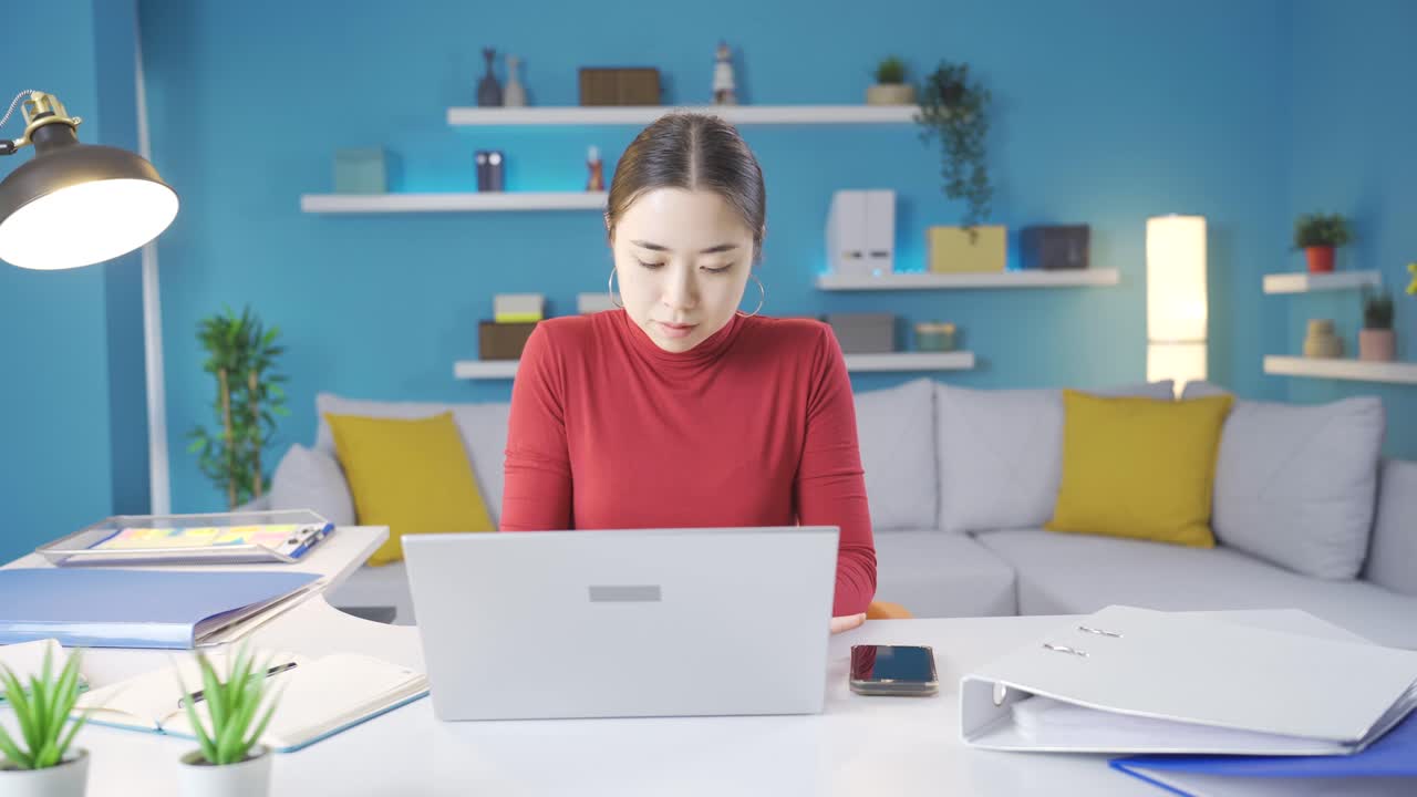 젊은 아시아 여성이 집에서 노트북에 집중하고 있습니다.