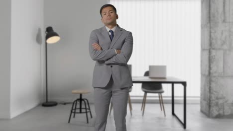 현대적인 오픈 플랜 사무실에 서 있는 슈트를 입은 심각한 사업가의 초상화