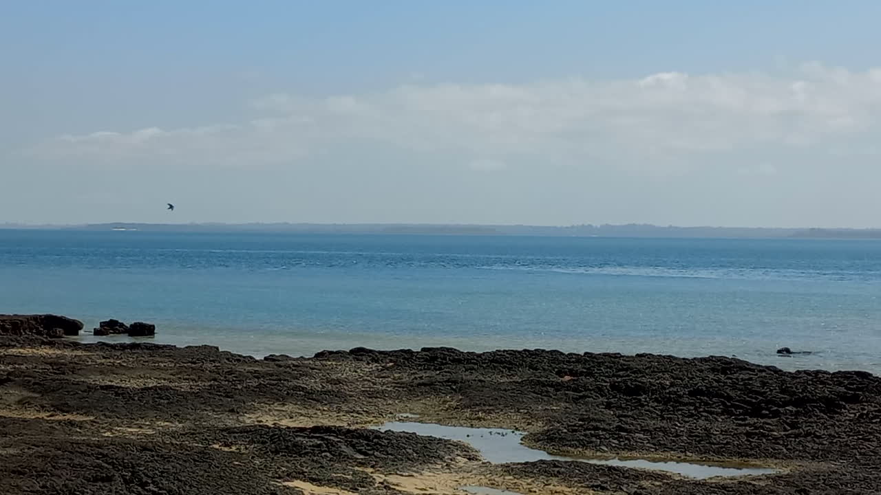 Beach with blue water and black rock, Bubaque Island in the Bijagos archipelago, Guinea Bissau