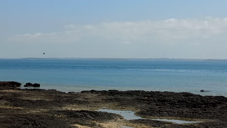 beach with blue water and black rock, bubaque island in the bijagos archipelago, guinea bissau