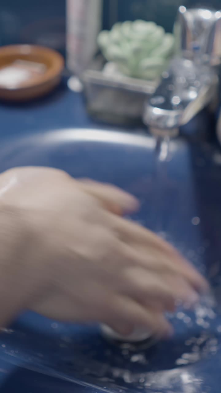 Person washing hands in a blue sink