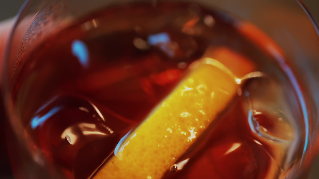 Primo piano di un cocktail Negroni con fetta d'arancia e cubetti di ghiaccio su un tavolo di legno