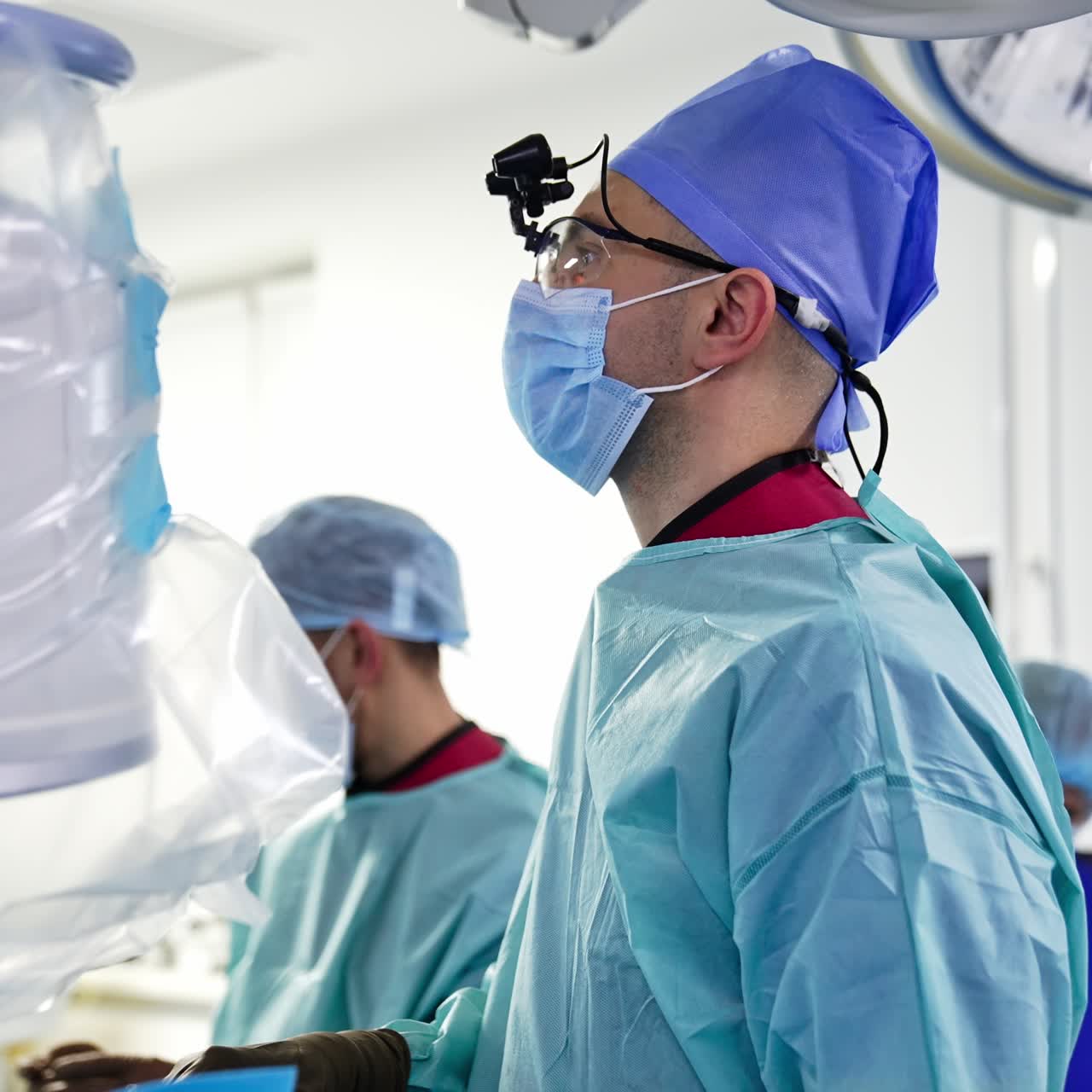 Portrait of a surgeon performing operation. Doctor looks straight in front of him. Team of medics helping the patient