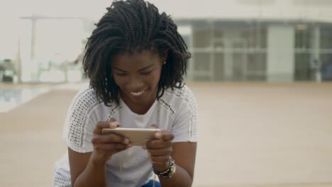 Lächelnde-Afroamerikanische-Frau,-Die-Auf-Dem-Smartphone-Tippt.